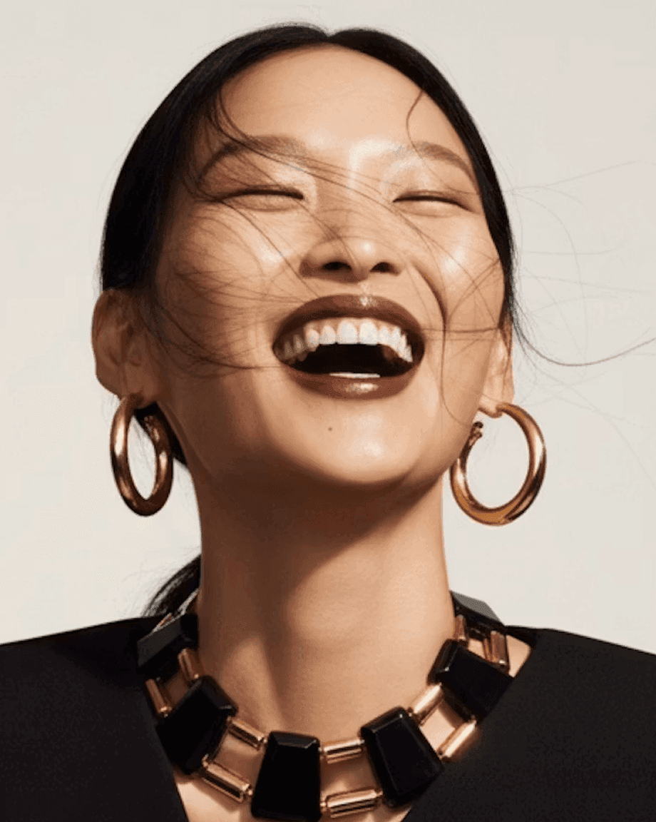 Woman laughing in gold hoop earrings and a bold necklace