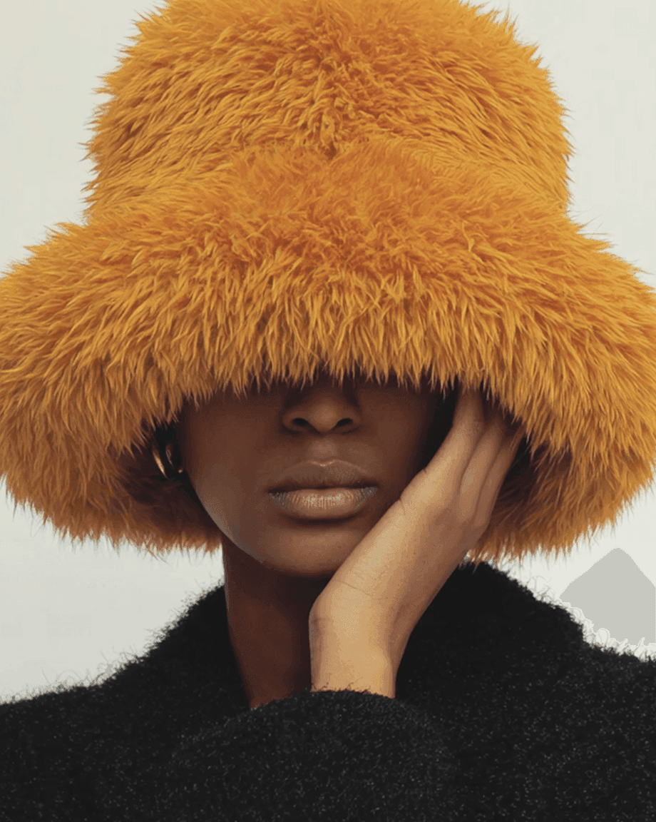Model in an orange fur bucket hat, hand on cheek